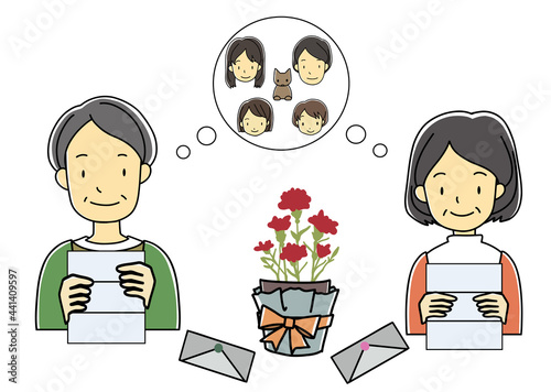 子供夫婦と孫からのカーネーションの鉢植えのプレゼントとメッセージを読む老夫婦（敬老の日等に）