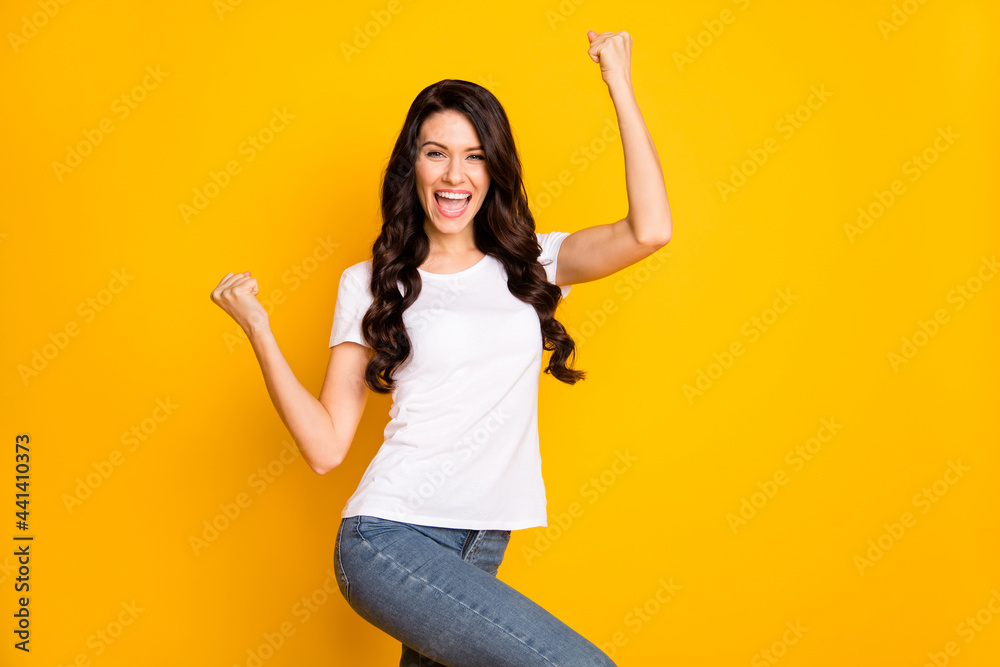 Photo of adorable lucky young lady dressed white t-shirt rising fists isolated yellow color background Photo of adorable lucky young lady dressed white t-shirt rising fists isolated yellow color background