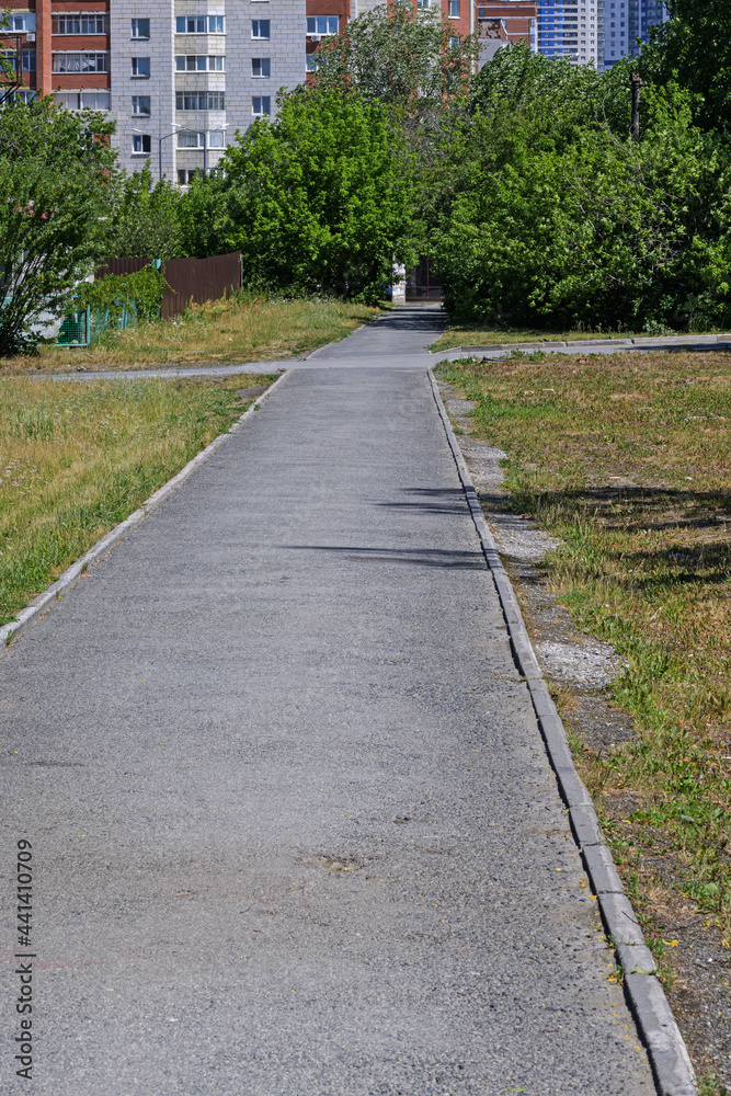 A deserted pedestrian path leads to residential buildings