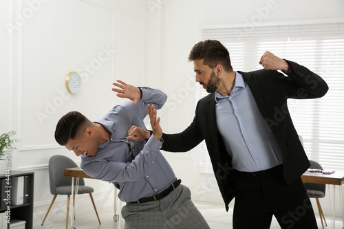 Emotional colleagues fighting in office. Workplace conflict photo