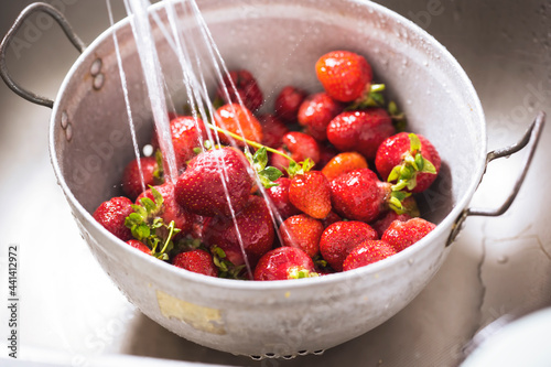 Fresh strawberries in colander, washed in water