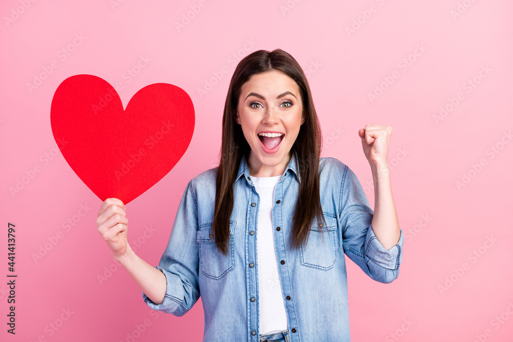 Photo portrait of female student keeping heart postcard gesturing like winner isolated on pastel pink color background Photo portrait of female student keeping heart postcard gesturing like winner isolated on pastel pink color background