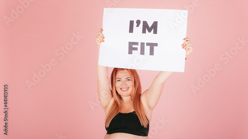 Happy confident woman with plus size body holding an i'm fit placard
