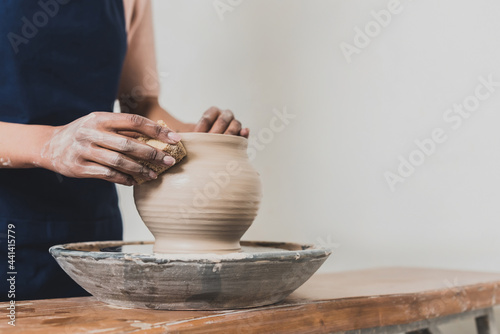 Fotografija partial view of young african american woman modeling wet clay pot on wheel with