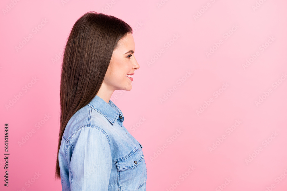 Side profile photo portrait of girl smiling in casual jeans shirt looking copyspace isolated on pastel pink color background Side profile photo portrait of girl smiling in casual jeans shirt looking copyspace isolated on pastel pink color background