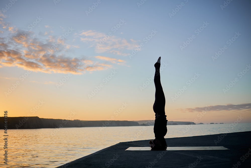 woman practicing a difficult yoga pose during sunset time