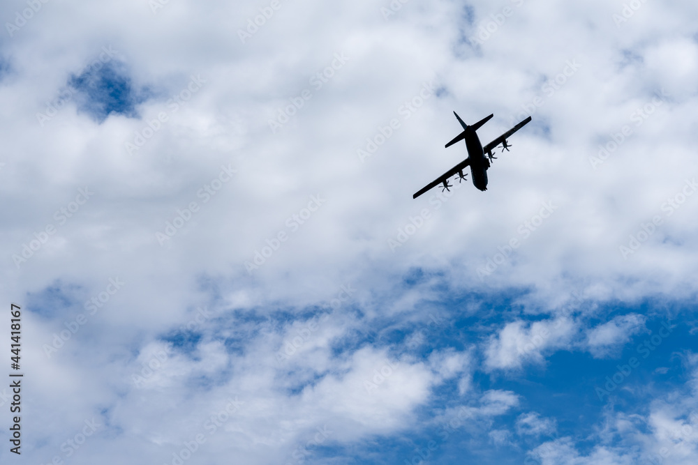silhouette of an old four propeller airplane against a backdrop of white clouds and blue sky silhouette of an old four propeller airplane against a backdrop of white clouds and blue sky