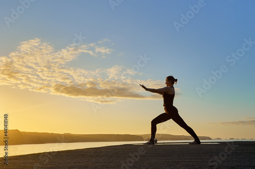 silhouette of Caucasian woman making a posture of the yoga warrior