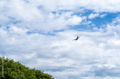 silhouette of an old four propeller airplane against a backdrop of white clouds and blue sky
