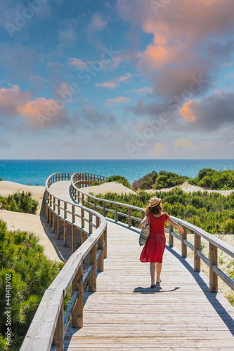 Girl with red dress on the wooden path to Playa Moncayo in Guardamar del Segura next to Torrevieja, Alicante. Community of Valencia. Spain, holidays in the Mediterranean photo