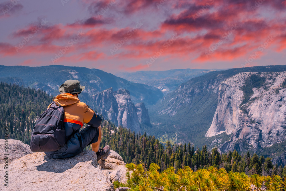 A young winged seated Taft point looking at Yosemite National Park and El Capitan in sunset. United States