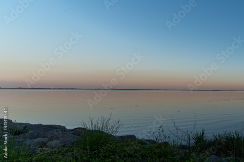 view of a picturesque coastline at sunset with a calm ocean and reeds in the foreground