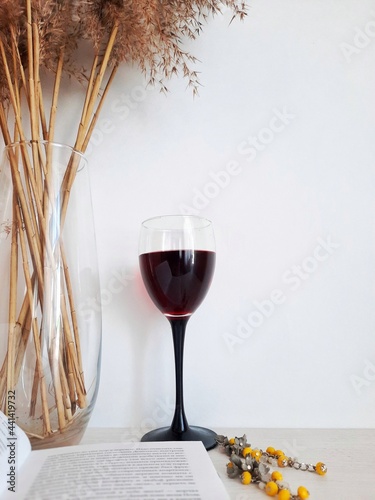 Books, glass of red wine on a wooden table light background relax mobile photo