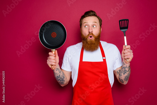 surprised chef with beard and red apron is ready to cook