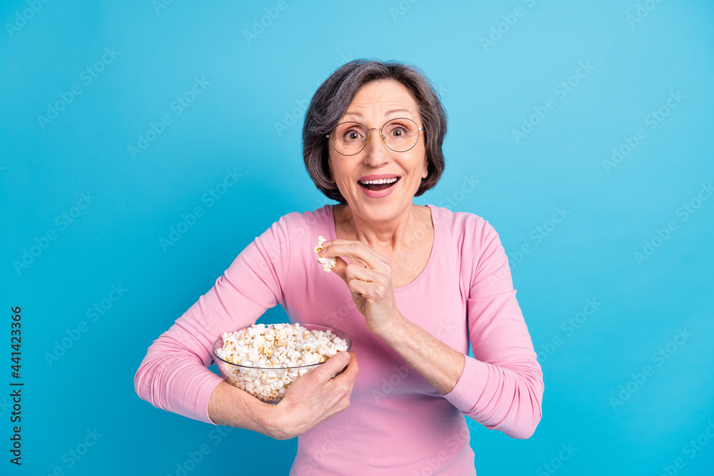 Photo of happy excited amazed shocked amazed woman eat popcorn hear good news isolated on blue color background Photo of happy excited amazed shocked amazed woman eat popcorn hear good news isolated on blue color background