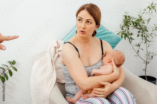 Unexperienced mother with sleeping newborn baby is listening to someone's advices