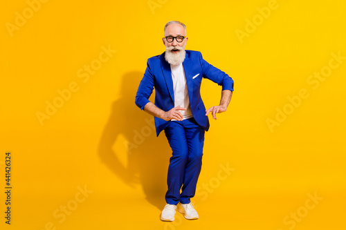 Full length body size photo of overjoyed cool senior man chilling relaxing at party isolated on vibrant yellow color background