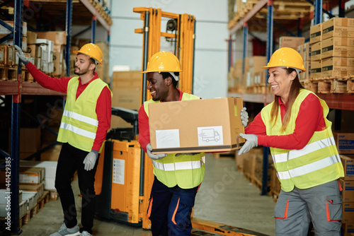 Positive diverse workers unloading boxes in warehouse photo