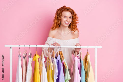 Photo portrait of red haired girl selecting clothes in boutique smiling happy isolated pastel pink color background