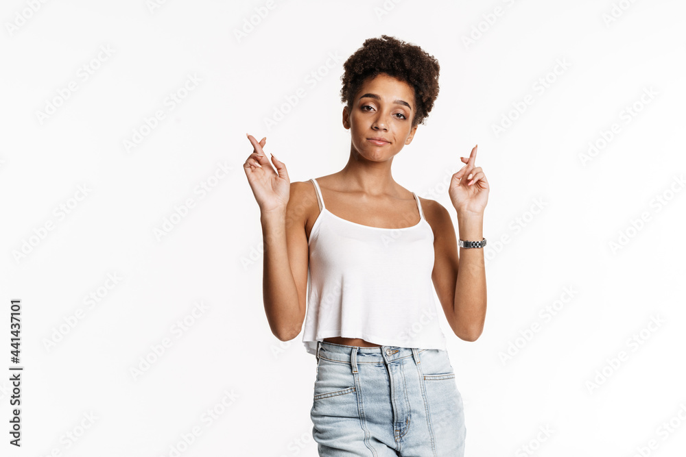 Young black woman in tank top holding fingers crossed for good luck