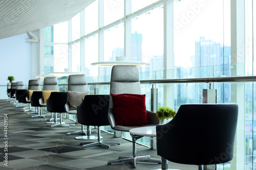 View of contemporary modern glass wall business meeting room in skyscraper high above city urban downtown with bright natural light