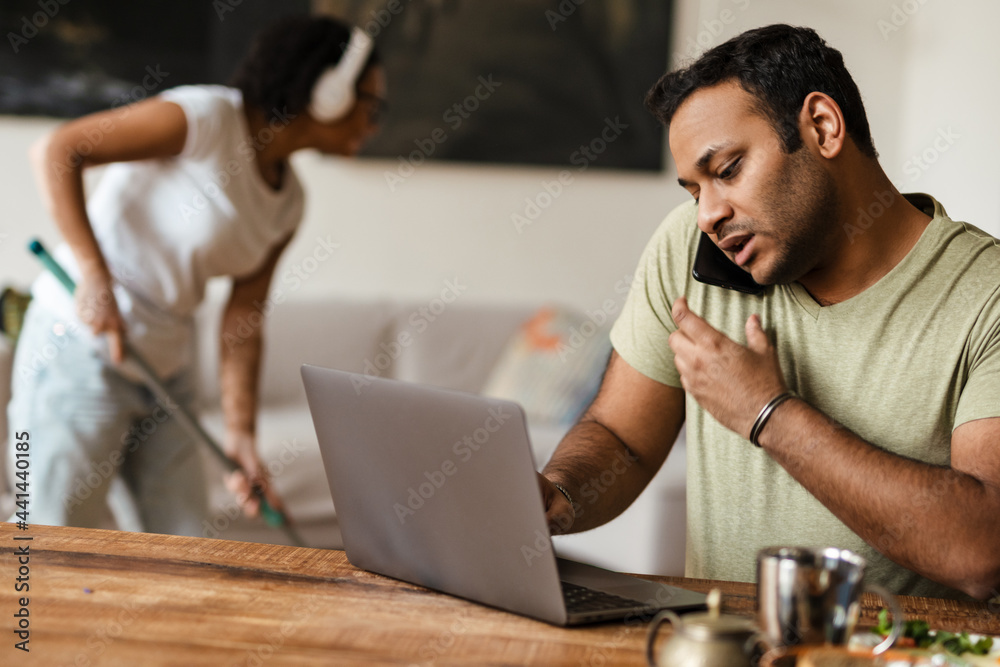 Middle eastern man talking on mobile phone while working with laptop Middle eastern man talking on mobile phone while working with laptop