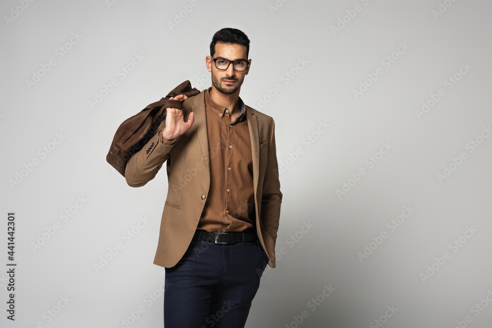 Muslim businessman in eyeglasses holding handbag on grey background Muslim businessman in eyeglasses holding handbag on grey background