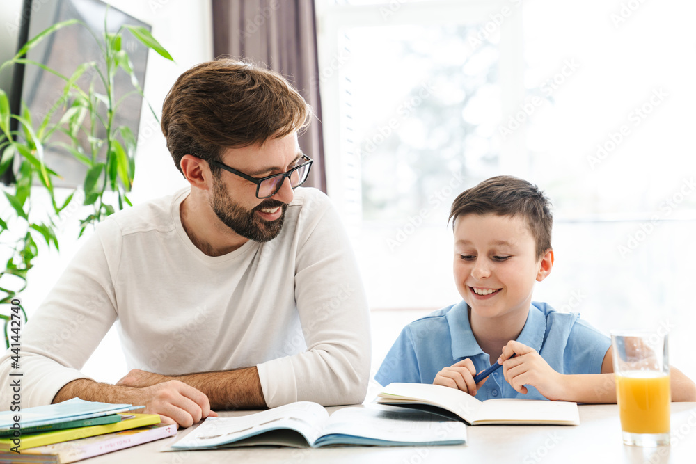 Mid aged father and his preteen son doing homework Mid aged father and his preteen son doing homework