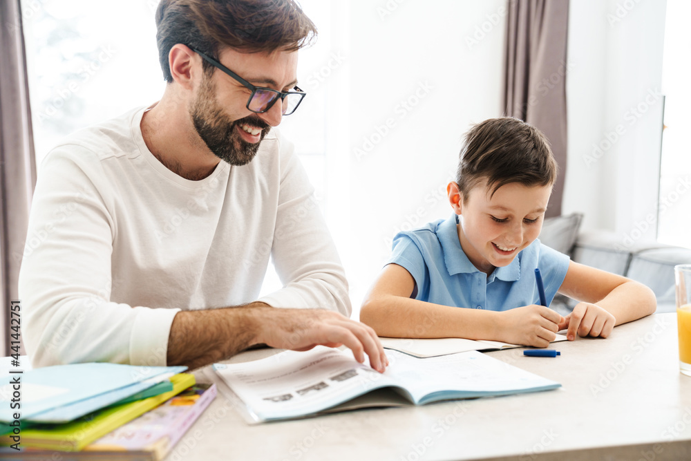 Mid aged father and his preteen son doing homework