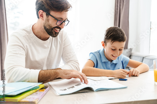 Mid aged father and his preteen son doing homework