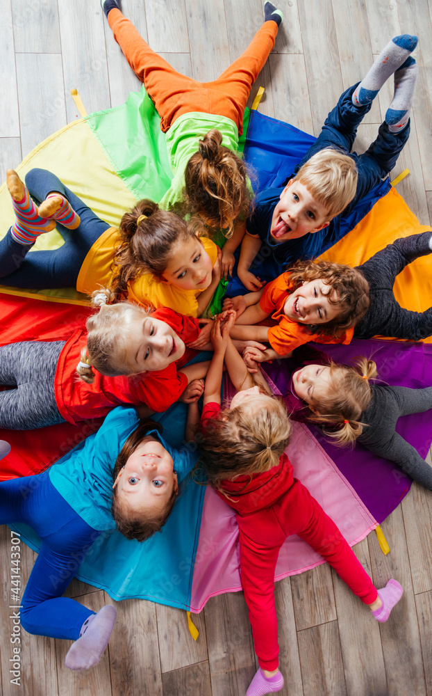 Cheerful children playing team building games on a floor - obrazy, fototapety, plakaty 