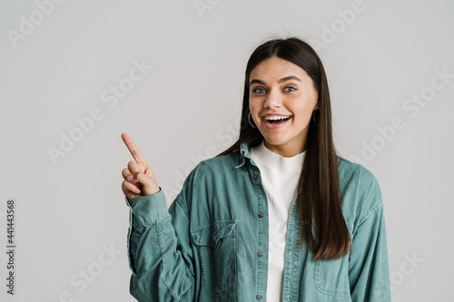 Young brunette woman smiling and pointing finger aside