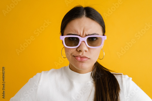 Bild auf Leinwand Young displeased woman in sunglasses frowning and looking at camera
