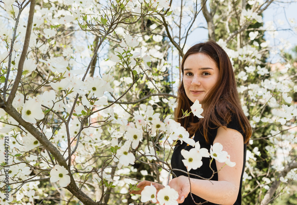 Beautiful young girl in on white background of a beautiful flowering plant Cornus florida Beautiful young girl in on white background of a beautiful flowering plant Cornus florida