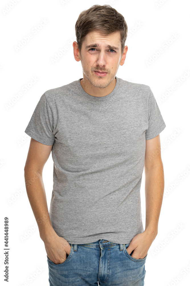Young handsome tall slim white man with brown hair looks confident in gray shirt in blue jeans isolated on white background Young handsome tall slim white man with brown hair looks confident in gray shirt in blue jeans isolated on white background