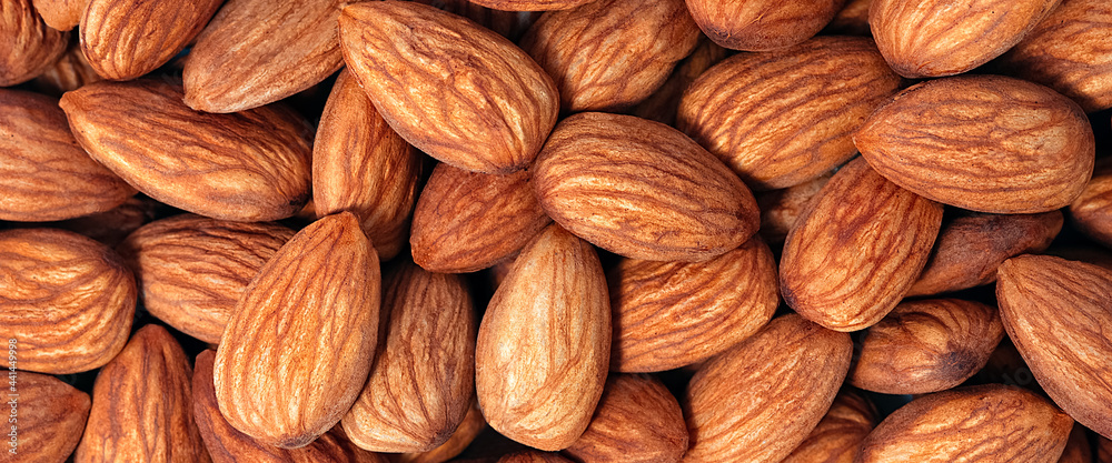 Background of almonds. Fried almonds. Scattered almond grains. Background for advertising Background of almonds. Fried almonds. Scattered almond grains. Background for advertising