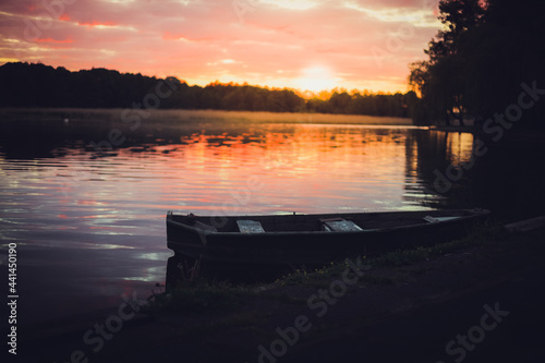Pink sunset on the lake with an old boat. Blurred natural background, Sunset sky over lake