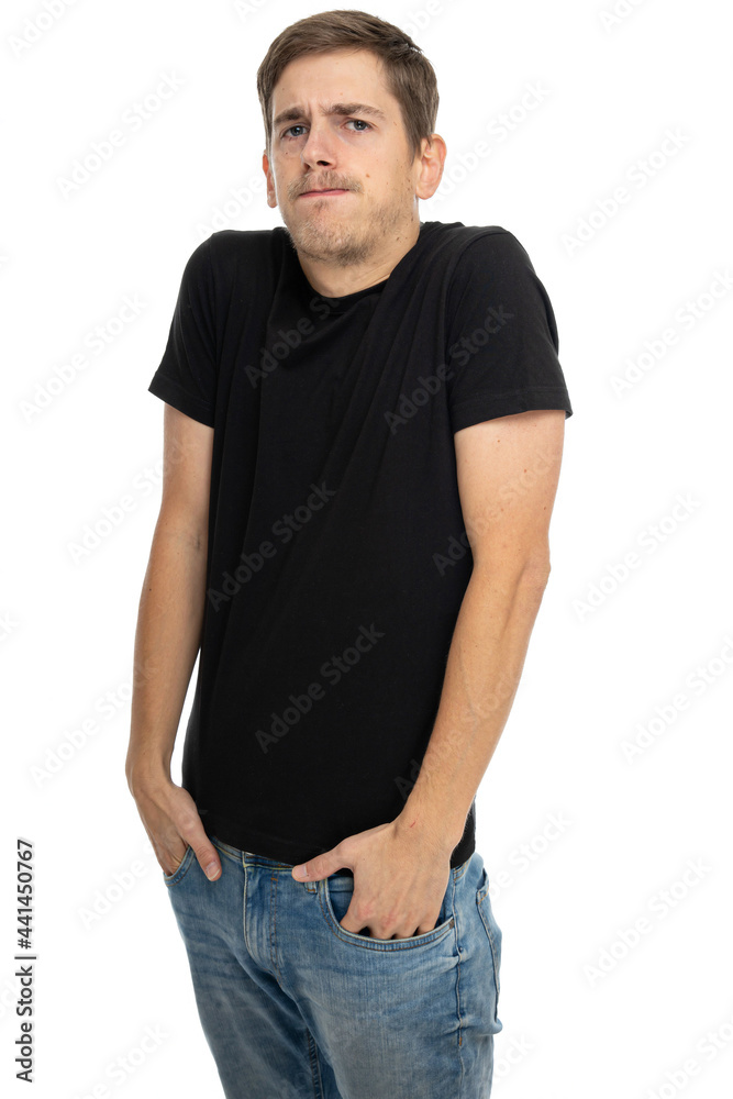 Young handsome tall slim white man with brown hair with lifted shoulders in black shirt in blue jeans isolated on white background Young handsome tall slim white man with brown hair with lifted shoulders in black shirt in blue jeans isolated on white background