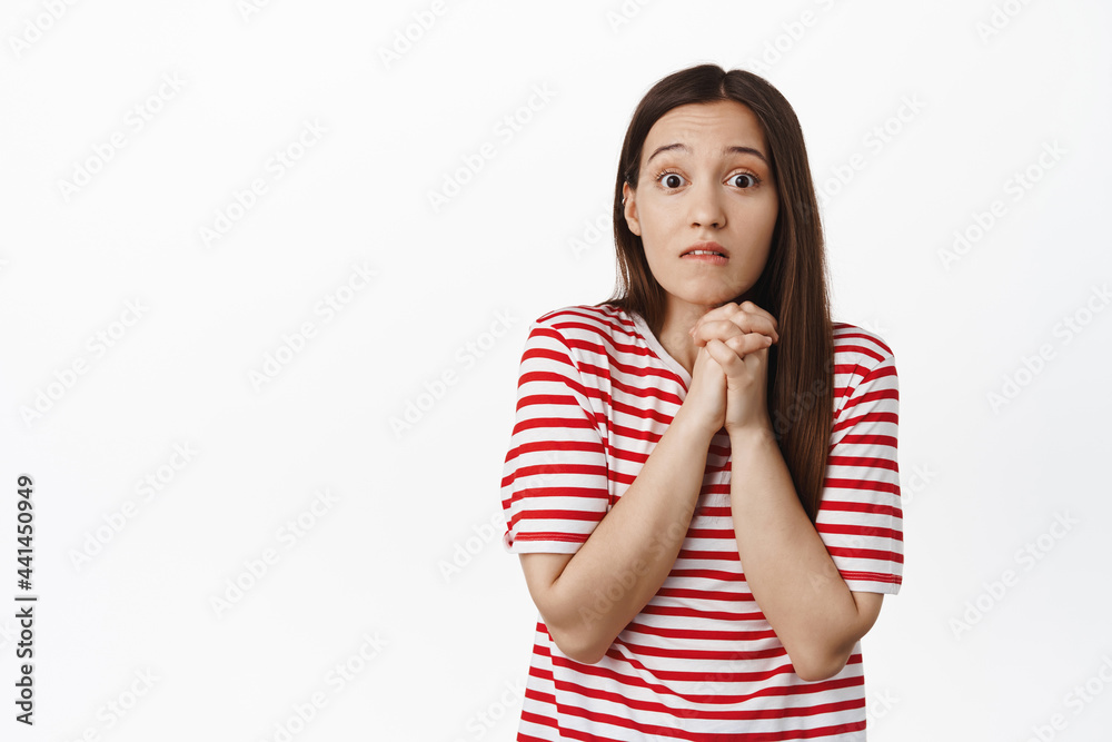 Cute clingy girl bites lip, looking hopeful, wanting something, gazing with desire and temptation, wants to have smth on sale, standing against white background Cute clingy girl bites lip, looking hopeful, wanting something, gazing with desire and temptation, wants to have smth on sale, standing against white background
