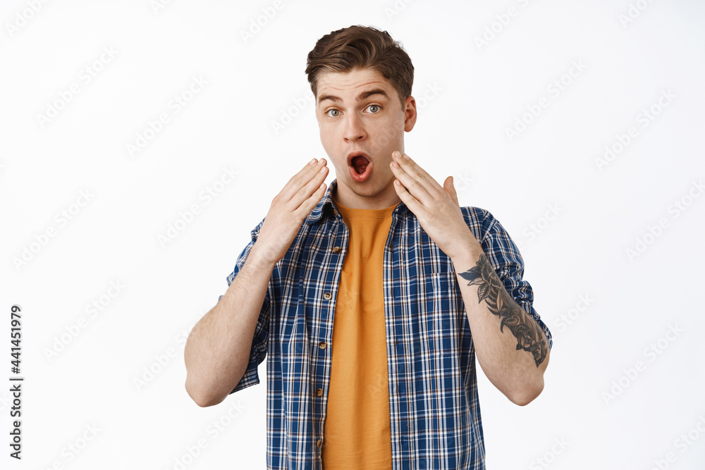 Image of shocked man drop jaw, say wow and stare startled, look in awe, holds hands near face, cant belive something, standing in disbelief against white background Image of shocked man drop jaw, say wow and stare startled, look in awe, holds hands near face, cant belive something, standing in disbelief against white background
