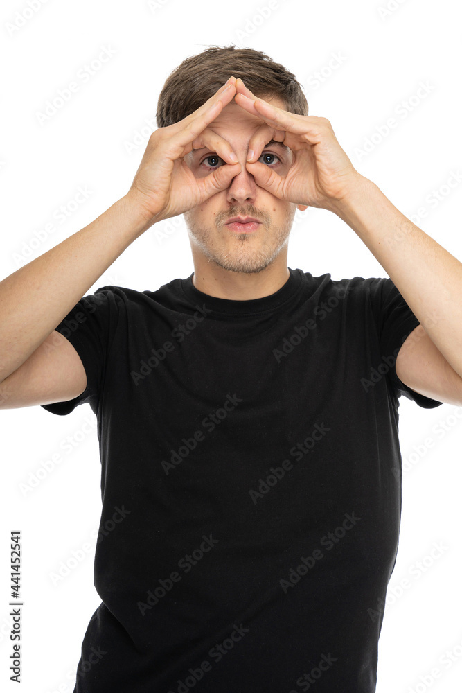 Young handsome tall slim white man with brown hair using his hands like a binoculars in black shirt isolated on white background Young handsome tall slim white man with brown hair using his hands like a binoculars in black shirt isolated on white background