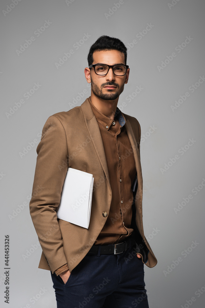 Fototapeta premium Muslim businessman with papers looking at camera isolated on grey