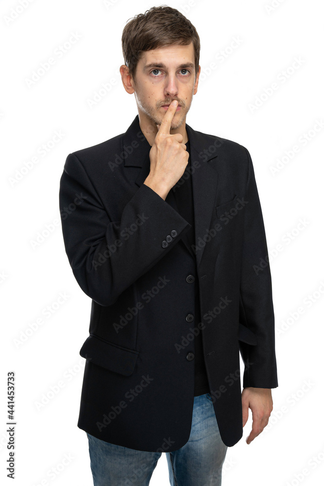 Young handsome tall slim white man with brown hair touching his lips in black blazer in blue jeans isolated on white background Young handsome tall slim white man with brown hair touching his lips in black blazer in blue jeans isolated on white background