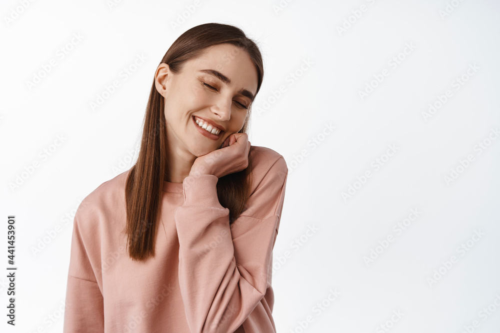 Close up portrait of dreamy and lovely girl touching face, close eyes and dreaming, feel tender and beautiful, thinking of something joyful, standing against white background Close up portrait of dreamy and lovely girl touching face, close eyes and dreaming, feel tender and beautiful, thinking of something joyful, standing against white background