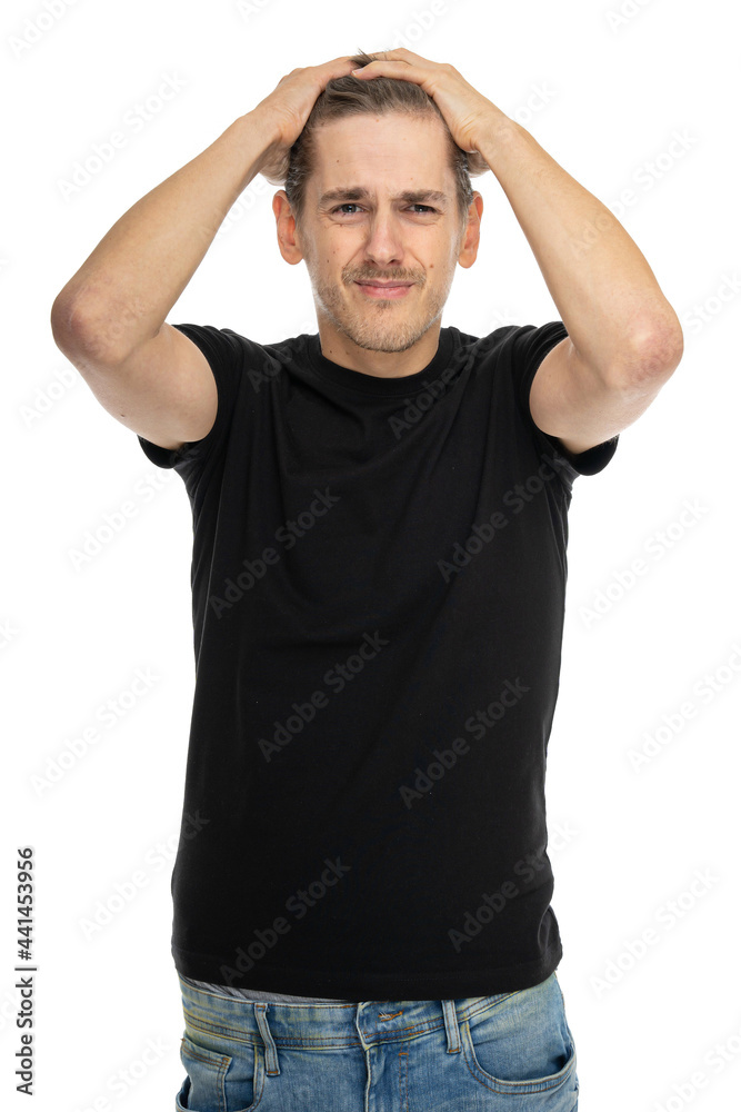 Young handsome tall slim white man with brown hair touching his head looking desperate in black shirt in blue jeans isolated on white background Young handsome tall slim white man with brown hair touching his head looking desperate in black shirt in blue jeans isolated on white background
