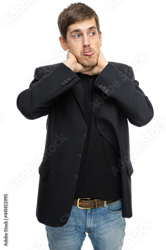 Young handsome tall slim white man with brown hair choking himself in black blazer in blue jeans isolated on white background