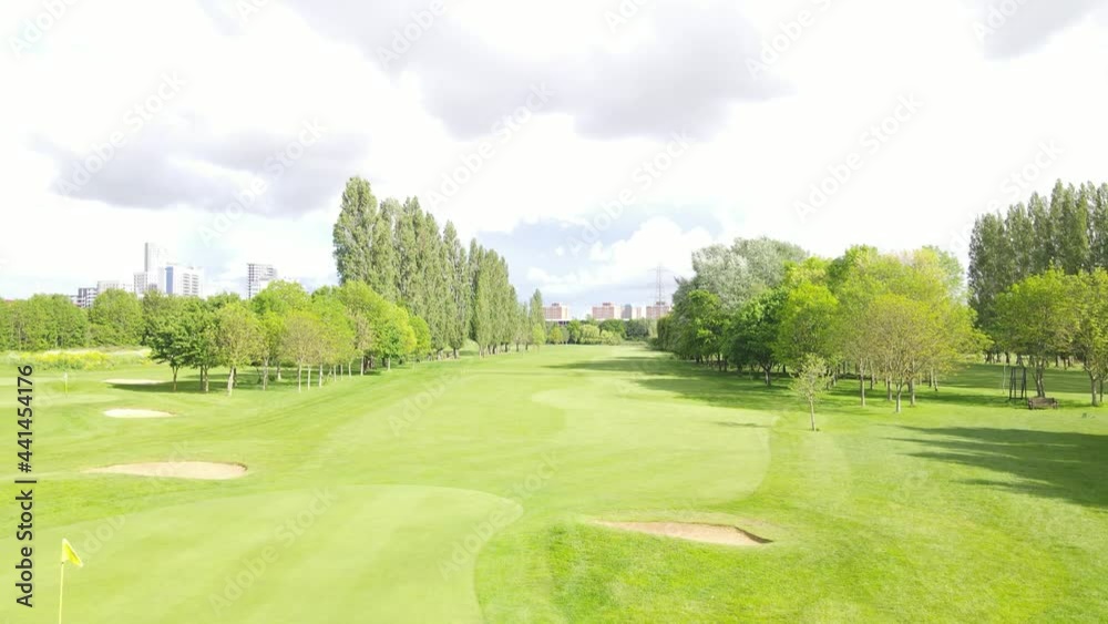Revealing shot of maintained sports area. Short cut grass on golf course with tall buildings behind. Overcast sky. Revealing shot of maintained sports area. Short cut grass on golf course with tall buildings behind. Overcast sky.