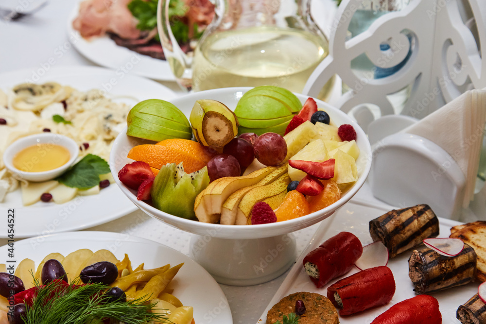 Slicing assorted fresh fruits on a plate on a tray in a restaurant. delicious dessert Slicing assorted fresh fruits on a plate on a tray in a restaurant. delicious dessert
