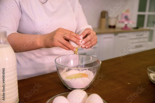 woman's hands prepare food, breaks an egg, baking, close-up