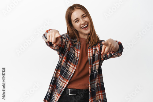 Portrait of excited young woman pointing fingers at camera, congratulating you, praising, inviting people to event, recruiting for job, standing happy against white background